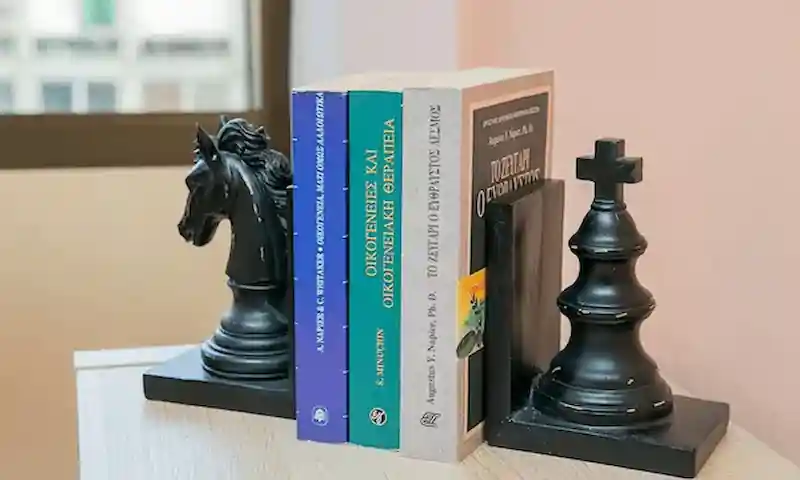 Βιβλία συστημικής και οικογενειακής θεραπείας στη βιβλιοθήκη με διακοσμητικά σκακιού
